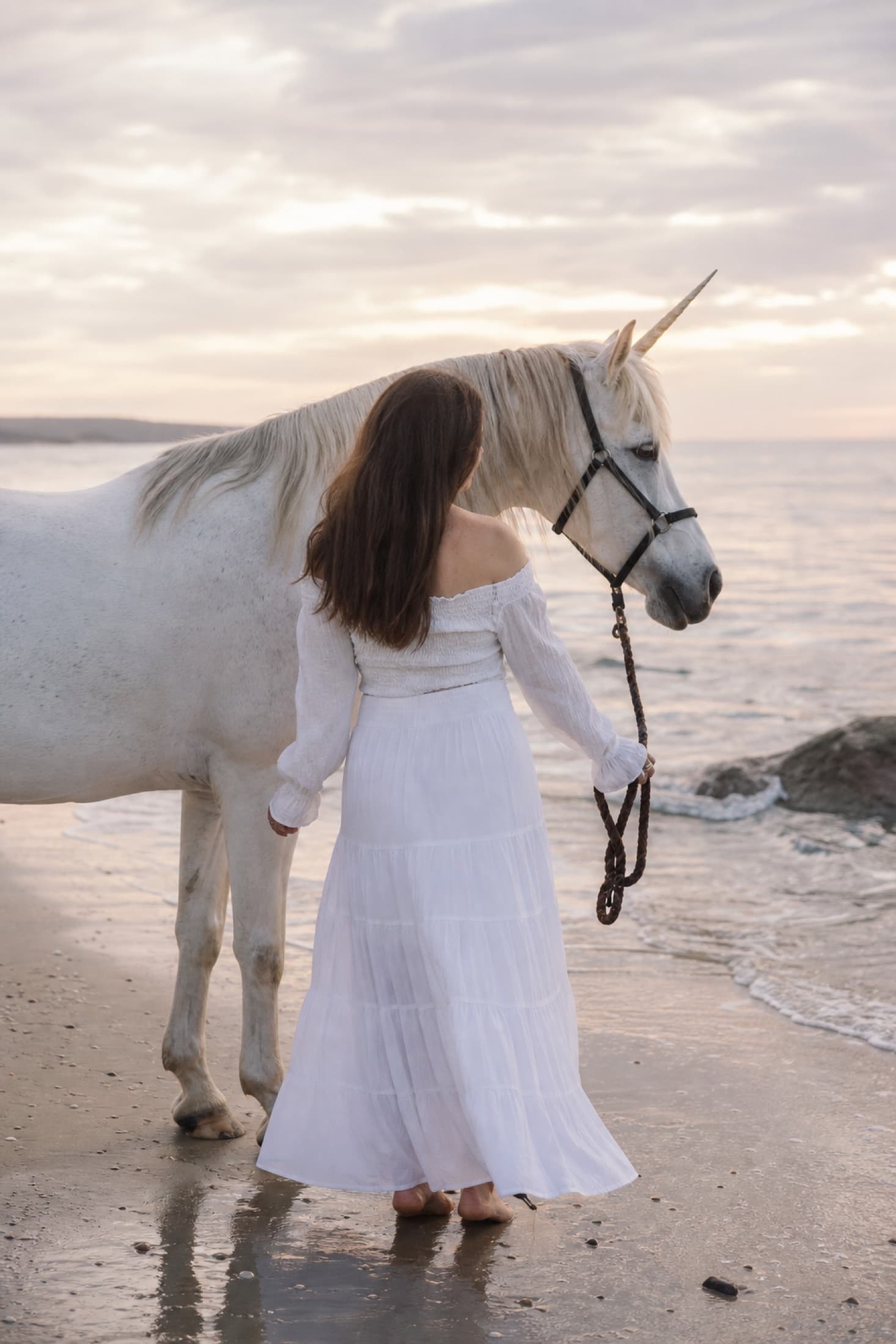 Quiet photo of a woman with unicorn on the beach